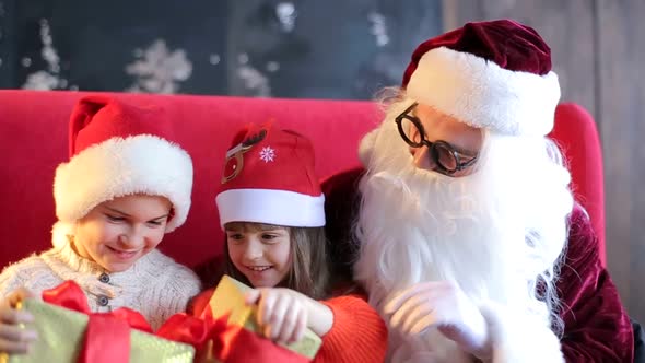 Little children sitting on authentic Santa Claus' knees indoors