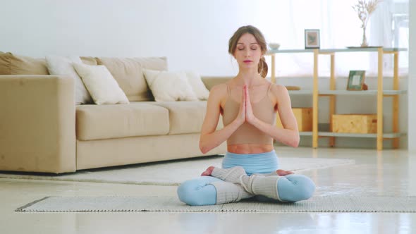 Attractive sportive girl sitting in lotus position with hands in namaste