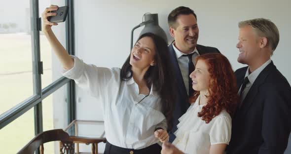 Friendly young people coworkers are taking selfie, posing together in workplace.