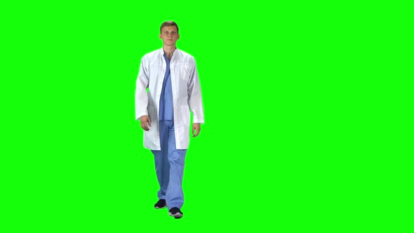 Medical Man in White Coat Going and Looking Forward Against a Green Background.
