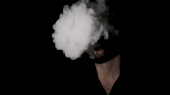 Man disappearing behind cigarette smoke, black background.