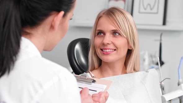 Conversation between smiling woman and dentist in dentist's clinic