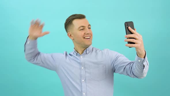 Portrait of Positive Man in a Blue Shirt Takes a Selfie with the Emotion of Happiness and Victory