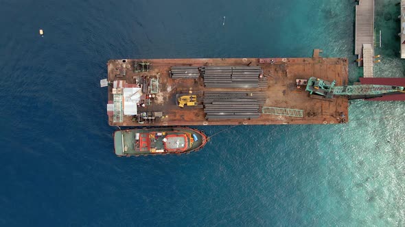 Ascending aerial shot of industrial pipe boat docking on harbor of Gili Trawangan,Asia.