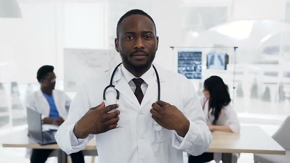 Young Male Doctor Putting Stethoscope on the Neck with Team