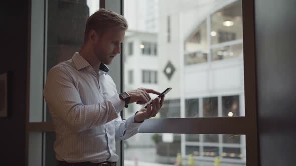 Businessman checking smartphone by the window