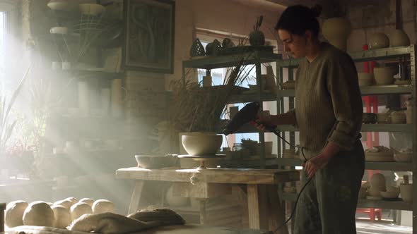 Woman Potter Is Drying Raw Clay Pot With Electric Dryer