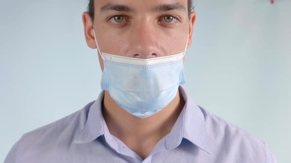Man Wearing Surgical Mask Below Nose Incorrectly, Closeup Looking at Camera