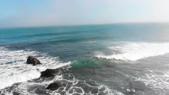 Aerial Cinematic shot of waves and Surfers Swimming on a sunny day in Pichilemu, Chile-4K