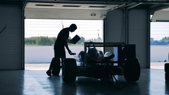 A Mechanic with a Laptop is Checking a Racing Car