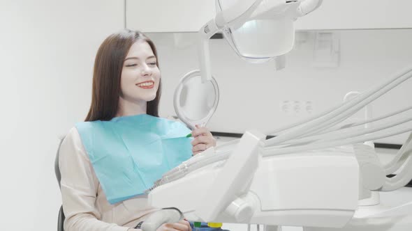 Cheerful Young Woman Smiling to the Camera Sitting in Dental Chair