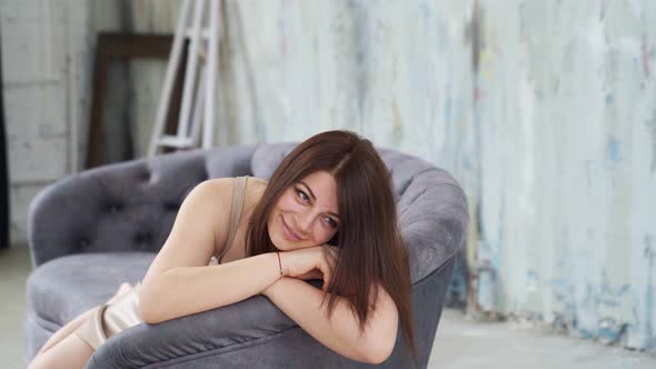 A Woman Lies on the Couch and Poses for a Photo Shoot in a Photo Studio Loft