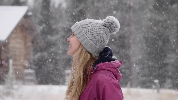 a medium shot of a young caucasian lady enjoying snow in slow motion