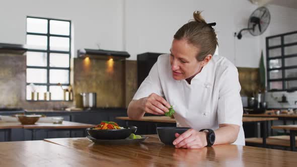 Caucasian female chef preparing a dish and smiling in a kitchen