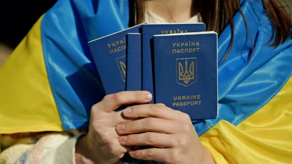 Woman Covered with the Flag of Ukraine with Ukrainian Passports in Her Hands