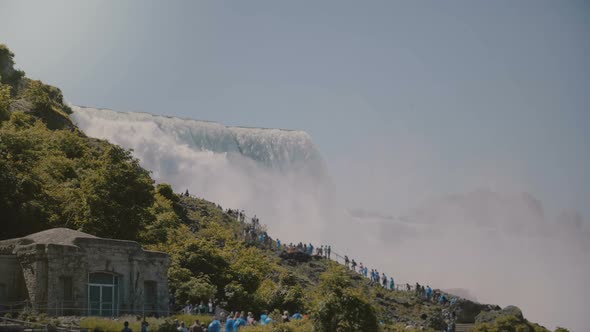 Cinematic POV Shot of Tourists in Raincoats Walking Up the Ladder at Epic Beautiful Niagara Falls