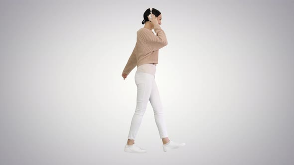 Smiling Female with Headphones Walking and Dancing To the Music on Gradient Background