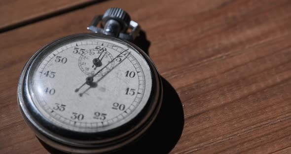 An Antique Stopwatch Lies on Wooden Table and Counts the Seconds