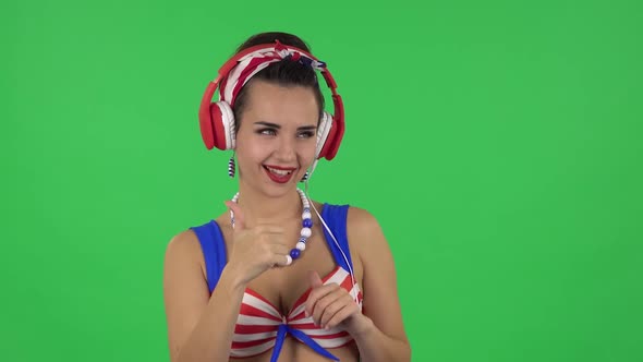 Portrait of Beautiful Girl in a Swimsuit Is Dancing and Enjoying Music in Big Red Headphones. Green