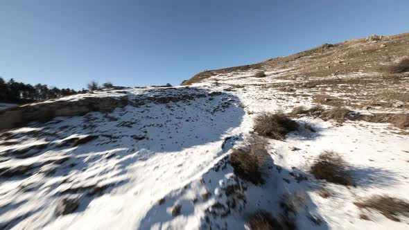 Flying close to a tree at high speed in a snow covered mountains landscape