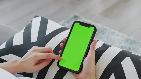 woman holding in hands a mock up smartphone with green screen for internet online.