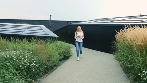 Woman with Smartphone Walking on Green Roof of Mall
