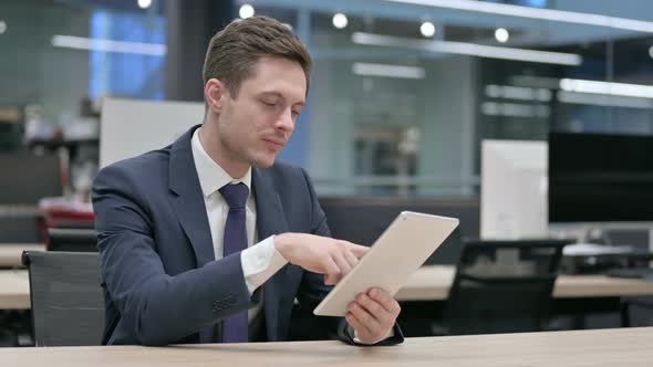 Businessman Using Tablet While Sitting in Office Sitting