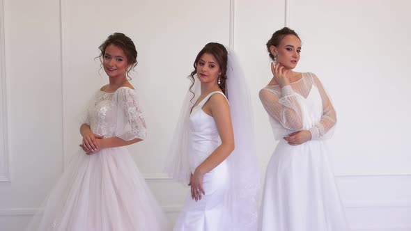 Three Beautiful Brides in White Dresses are Posing While Standing