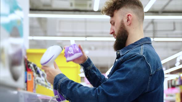 Shopping in Home Appliance Store Adult Man is Checking Garment Steamer