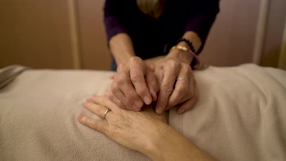 Detail of a professional acupuncturist inserting a needle into the hand of a mature caucasian woman