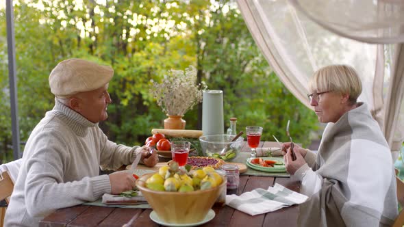 Retired Caucasian Couple Eating Simple Meal in Garden and Chatting