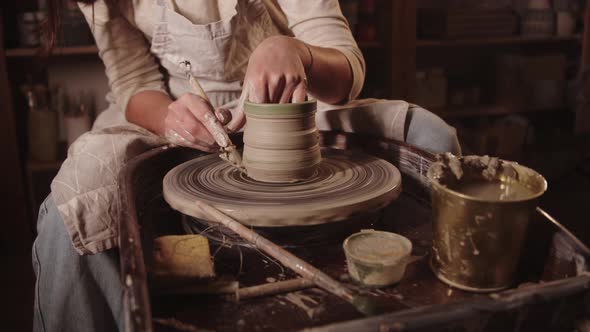 Young Woman Potter Cutting Off the Excess Out of Clay Pot