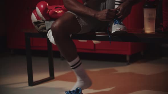 Black Young Man Boxer Putting on His Shoes in a Locker Room