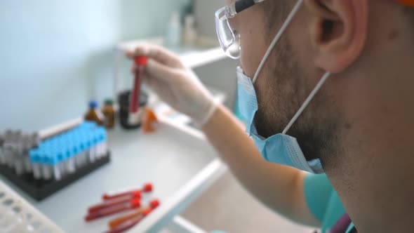 Profile of Scientist Testing Test Tube with Blood Sample To Coronavirus. Young Laboratory Worker in