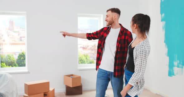 Joyful Cute Caucasian Young Wife and Husband Couple Thinking About Decoration Ideas for New