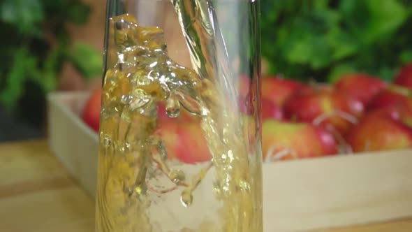 Apple Juice Is Poured Into the Jug on the Background of a Basket Full of Apples