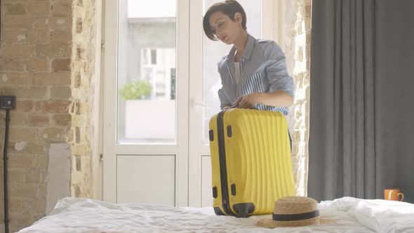 Confident Beautiful Woman Zipping Yellow Travel Bag and Leaving Hotel Room or Bedroom with Baggage