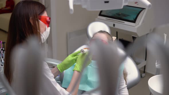 Little Cute Girl at Dentist Clinic Gets Dental Treatment to Fill a Cavity in a Tooth