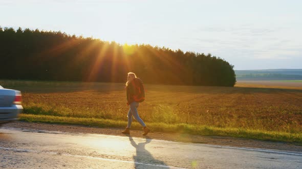 Girl Traveller with Backpack is Walking on Road