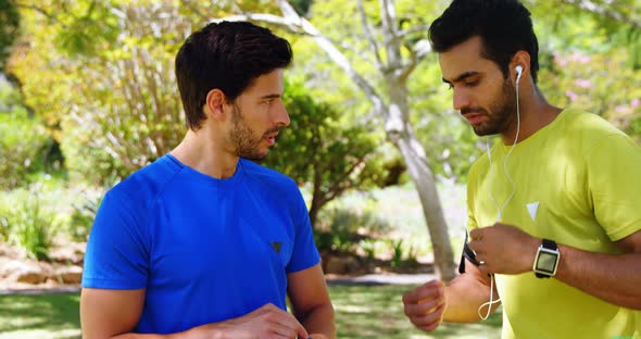 Two male joggers interacting with each other in park 4k