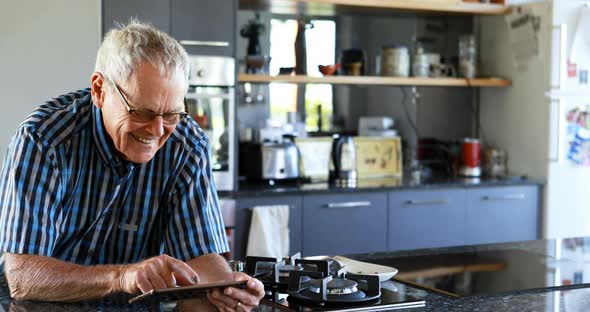 Senior man using mobile phone in kitchen 4k