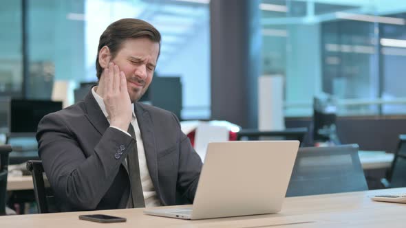 Businessman Having Toothache While Working on Laptop