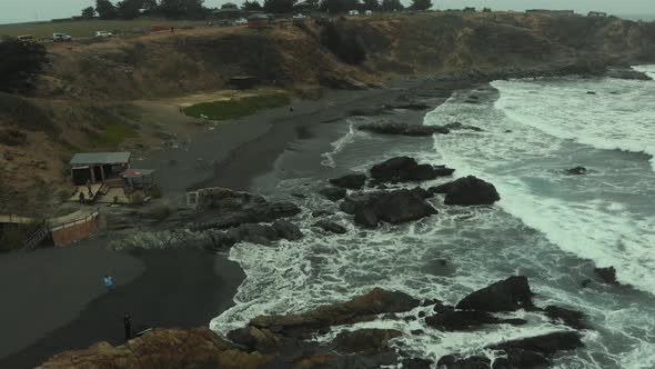 Aerial shot flying along the beach on a clody day in Pichilemu, Chile-4K