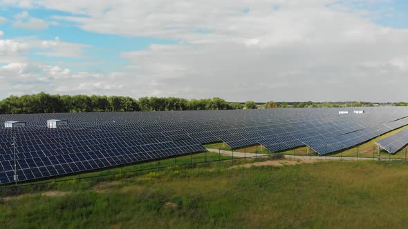 Aerial View of Solar Power Station. Panels Stand in a Row on Green Field. Summer