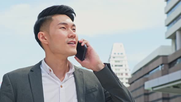 Asian young smart businessman talking in telephone in city walking outdoor to working office.