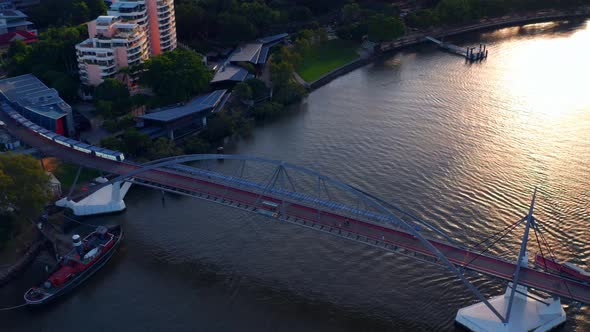 People Walking At Goodwill Bridge Over Brisbane River At Sunset In QLD, Australia. - aerial