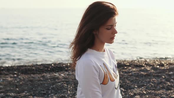 Brunette Woman Is Relaxing Alone on a Gravel Beach of Sea in Evening