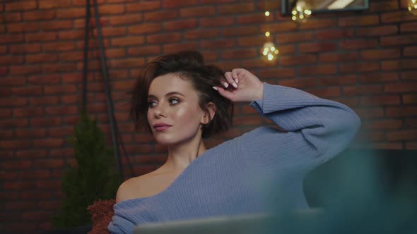 Glamorous Girl Relaxing on Cozy Sofa and Uses Laptop in Evening