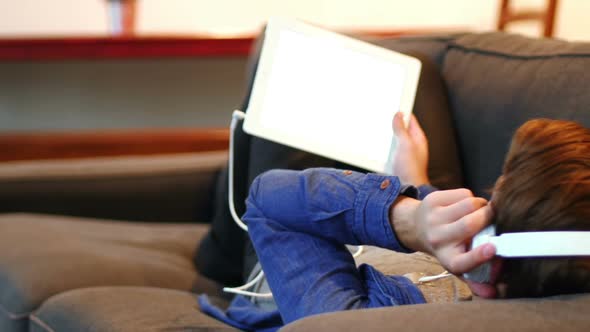 Man listening to music on digital tablet in living room