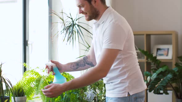 Man Spraying Houseplants with Water at Home